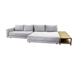 Lysgrå sofa med forlænget sæde og træbord til højre.